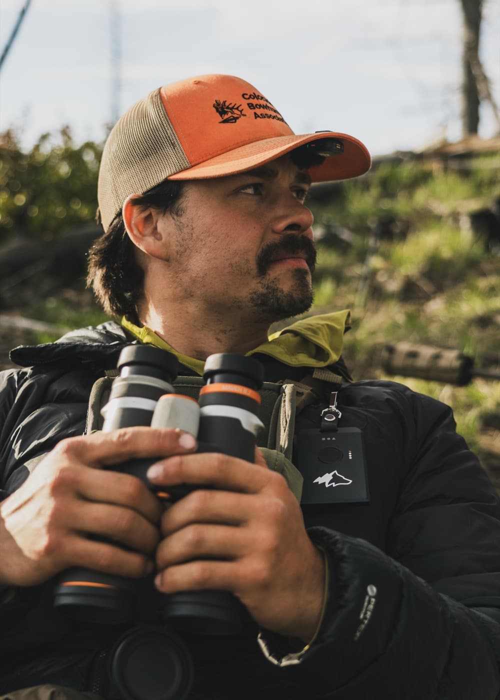 Hunter with binoculars and a Kiba Scout on his chest
